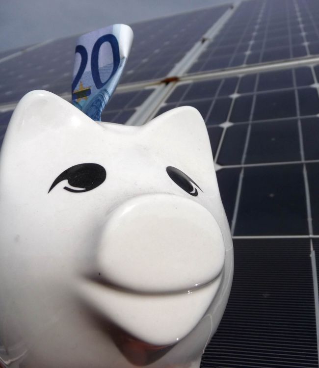Sparschwein mit 20 Euro Schein vor Solaranlage (oder Photovoltaikanlage)